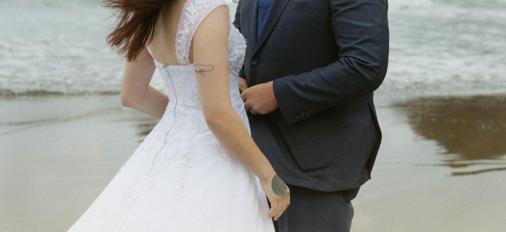 An intimate moment between newlyweds on a cloudy beach.