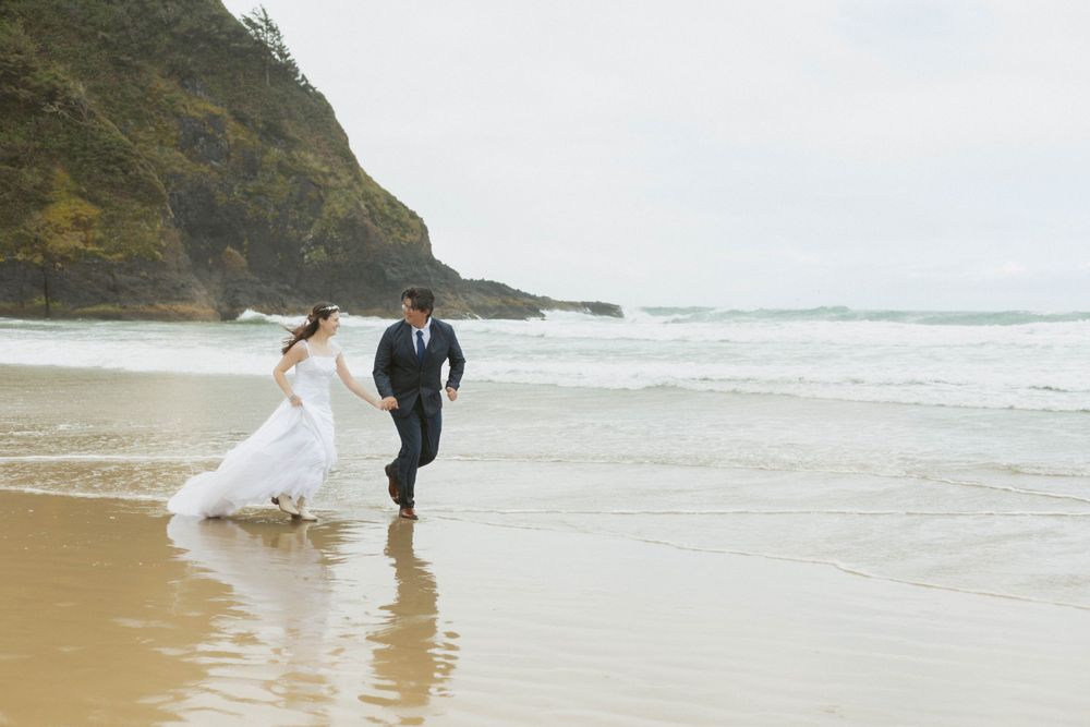 A romantic beach wedding photoshoot with waves and coastal cliffs in the background.