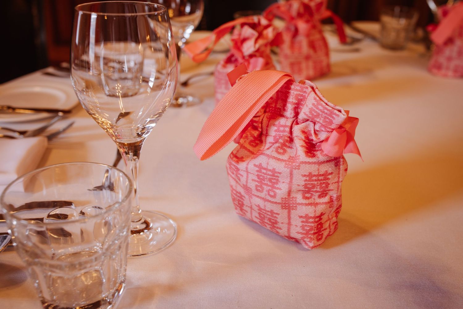 Wine glasses and pink party favors arranged on a formal dining table.