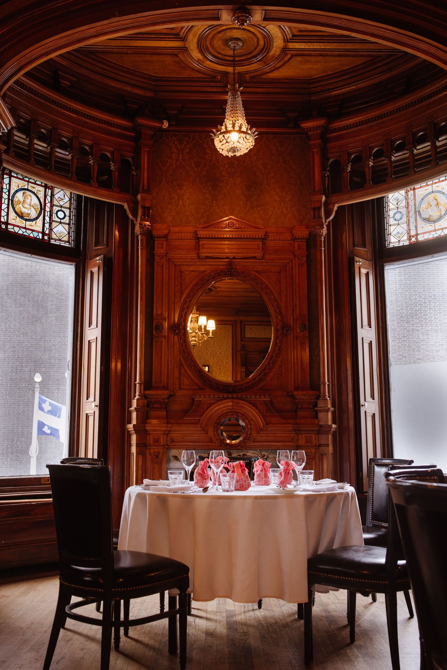 Elegant dining room with wood paneling, chandelier, and round table set for a special occasion.