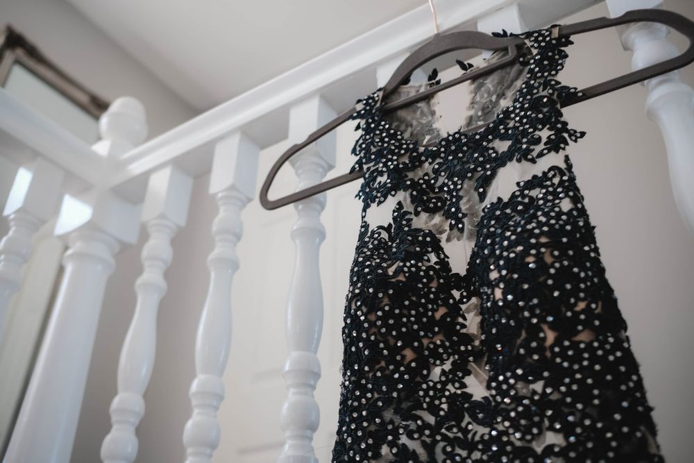 Detailed view of black sequined dress bodice hanging on white banister.