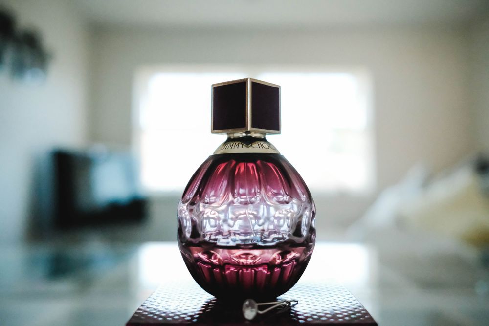 Elegant round perfume bottle with purple liquid photographed in natural light.