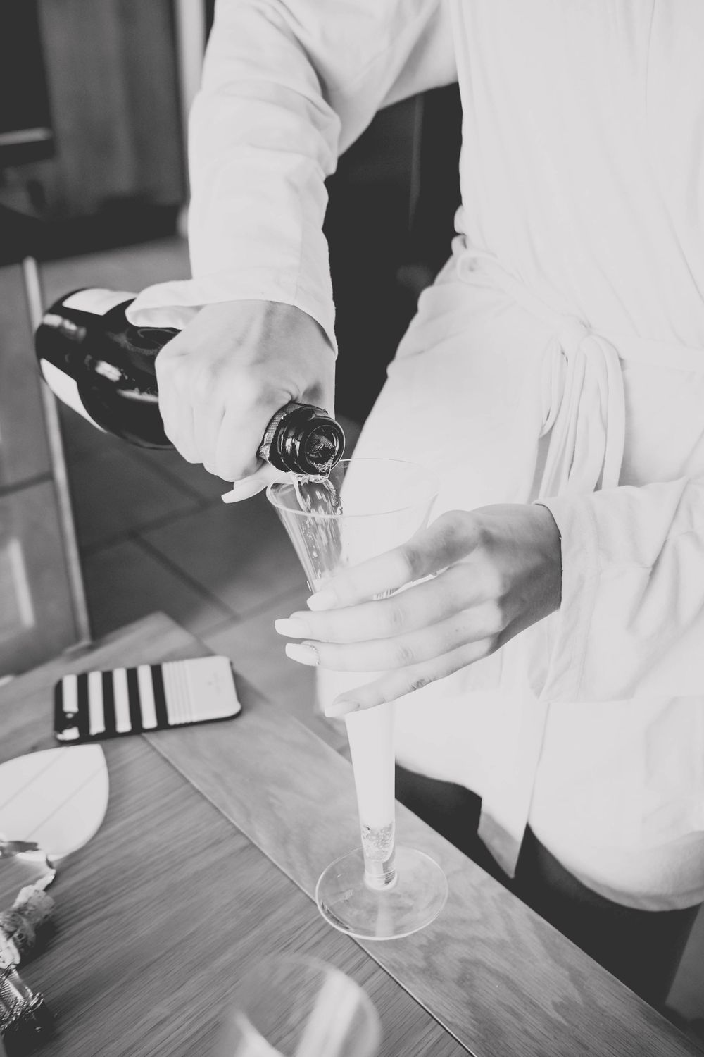 Close-up shot of hands pouring champagne into glass flute.