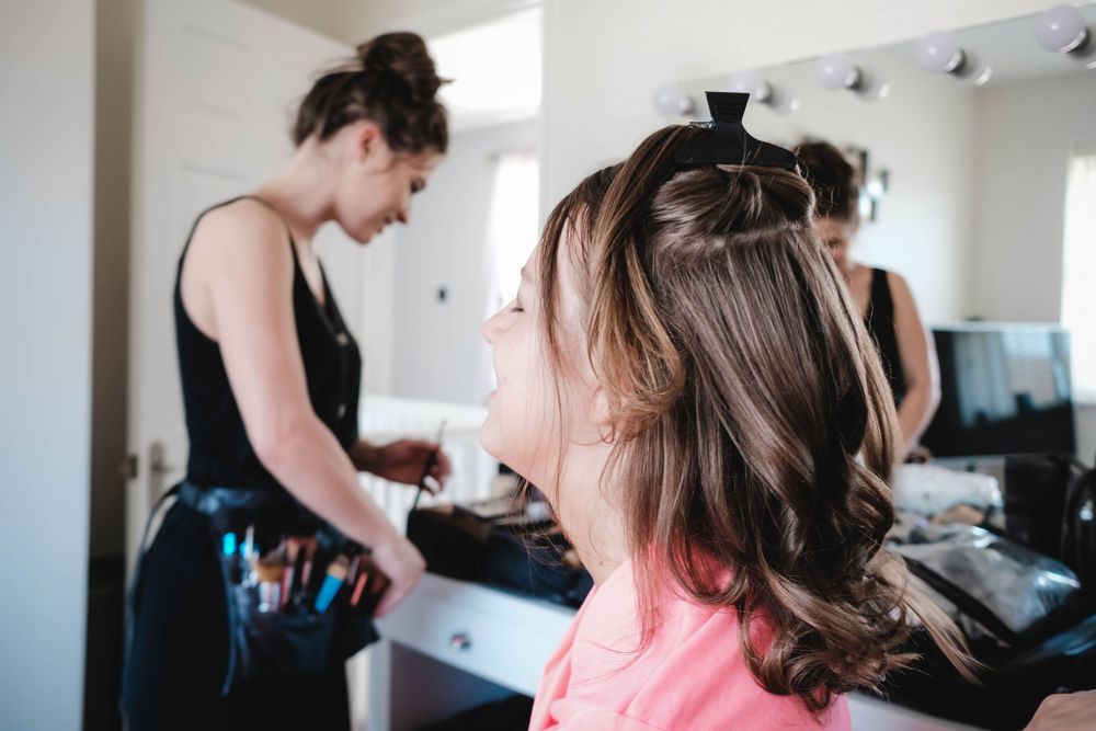 Professional hairstyling session in progress at well-lit salon with mirror backdrop.