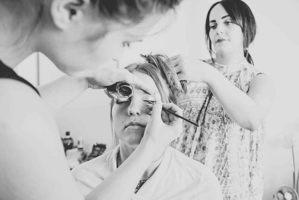 Intimate black and white capture of hair styling process in salon mirror.