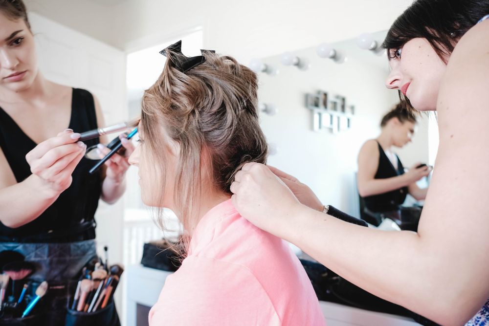 Stylists work together to create an elegant updo hairstyle in a bright salon setting.
