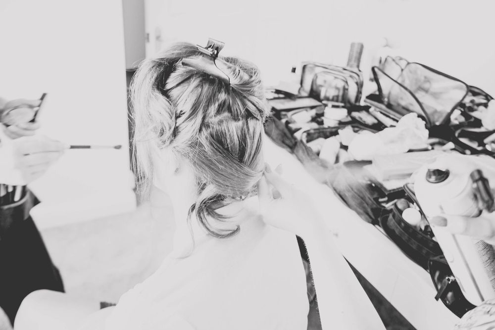 Black and white image shows detailed work on an intricate updo hairstyle.