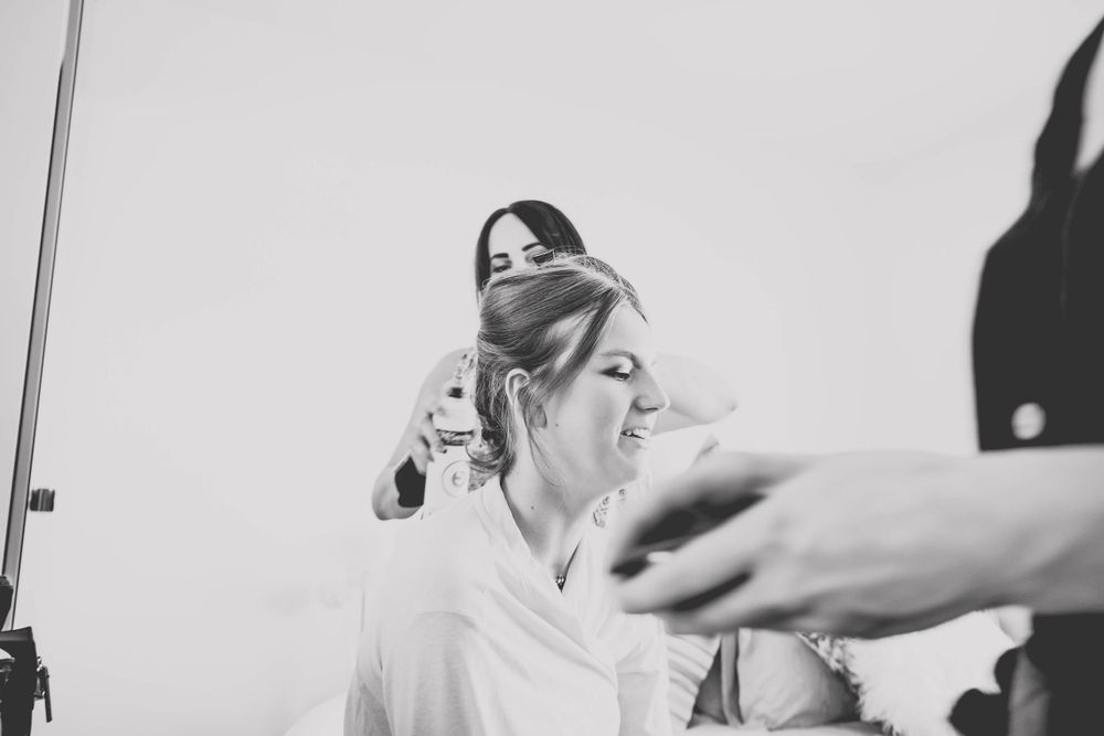 Stylists put finishing touches on an elegant updo hairstyle during preparation.