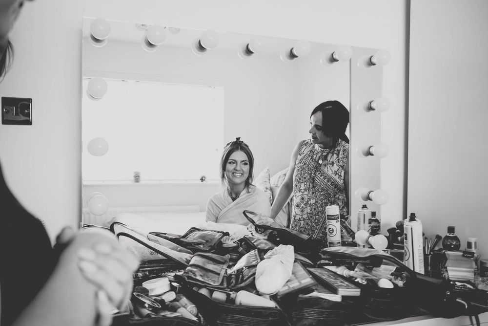 Black and white image of salon preparations with styling tools scattered on vanity counter.