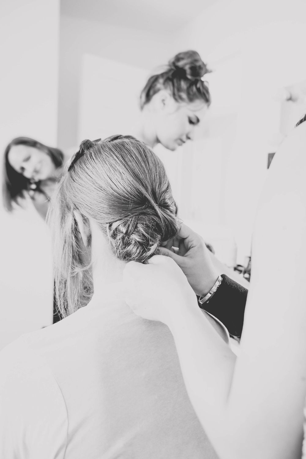 Black and white photograph capturing intimate styling moments in a bright makeup room.