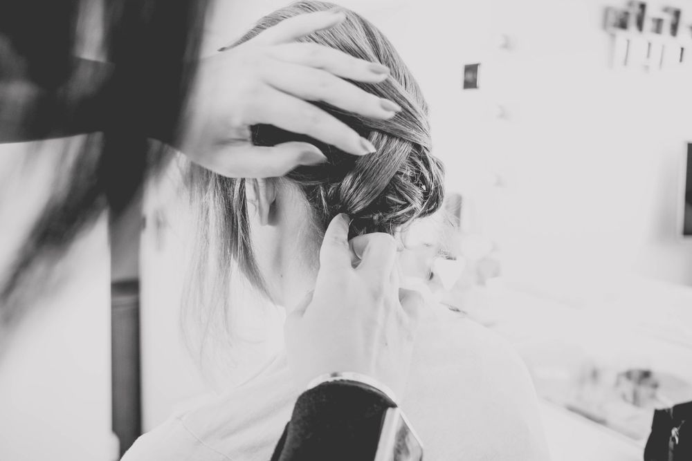Artistic black and white close-up of hands styling hair during preparation.