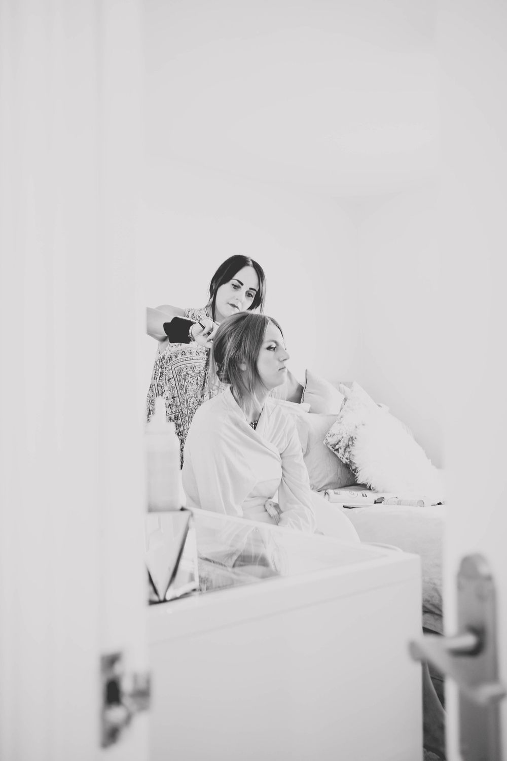 Black and white image of styling session in front of bright window and mirror.