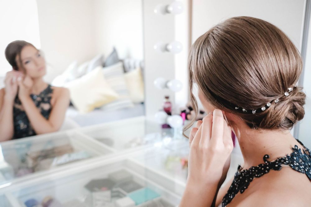 Elegant hairstyling session reflected in a makeup vanity mirror with professional lighting.
