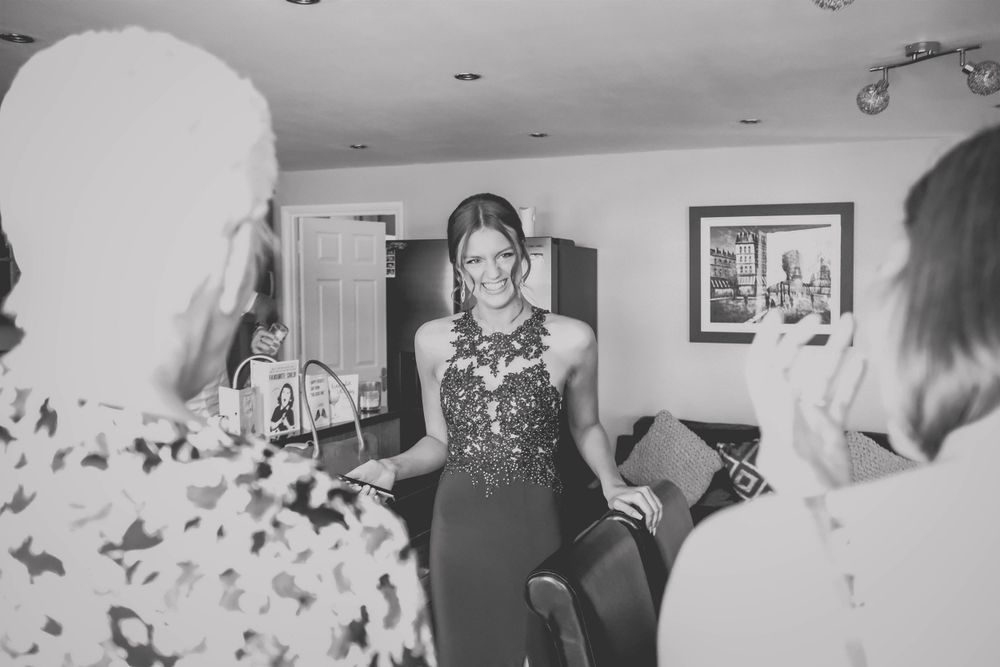 Black and white photo of formal dress reveal moment in an indoor setting.
