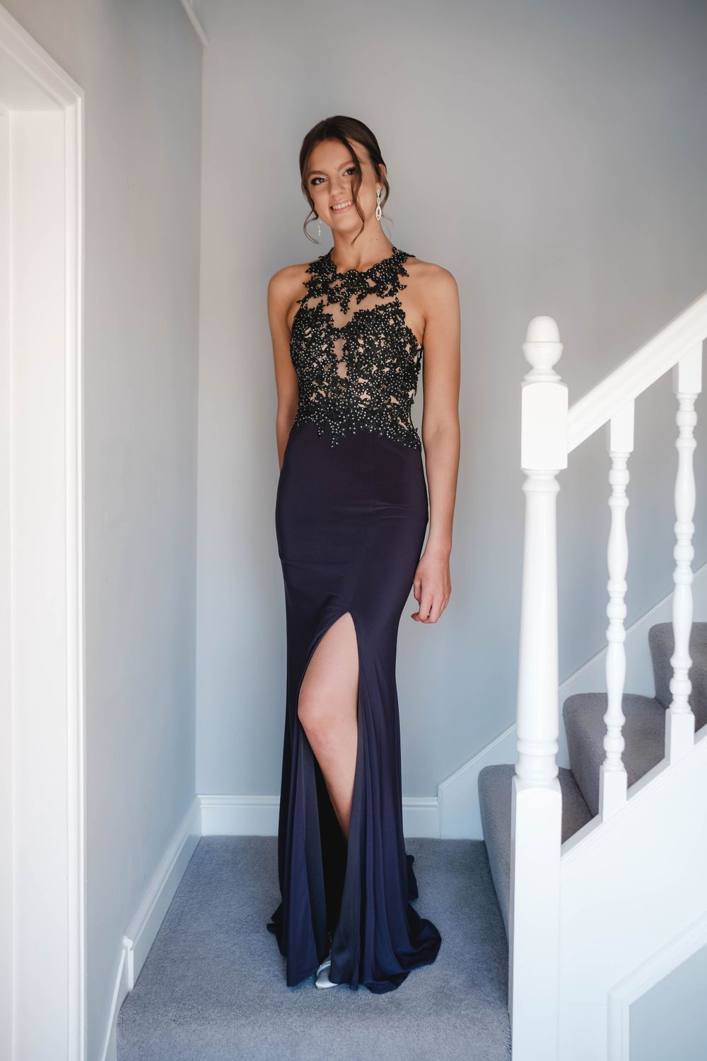 Full-length view of a navy evening gown with beaded lace bodice and dramatic side slit.
