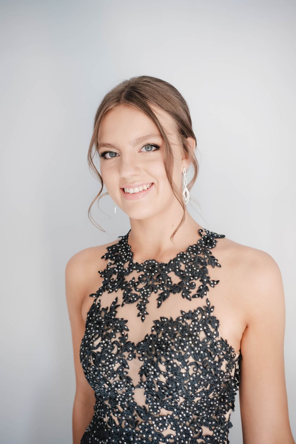 Close-up portrait highlighting delicate beadwork and lace detail on formal evening attire.