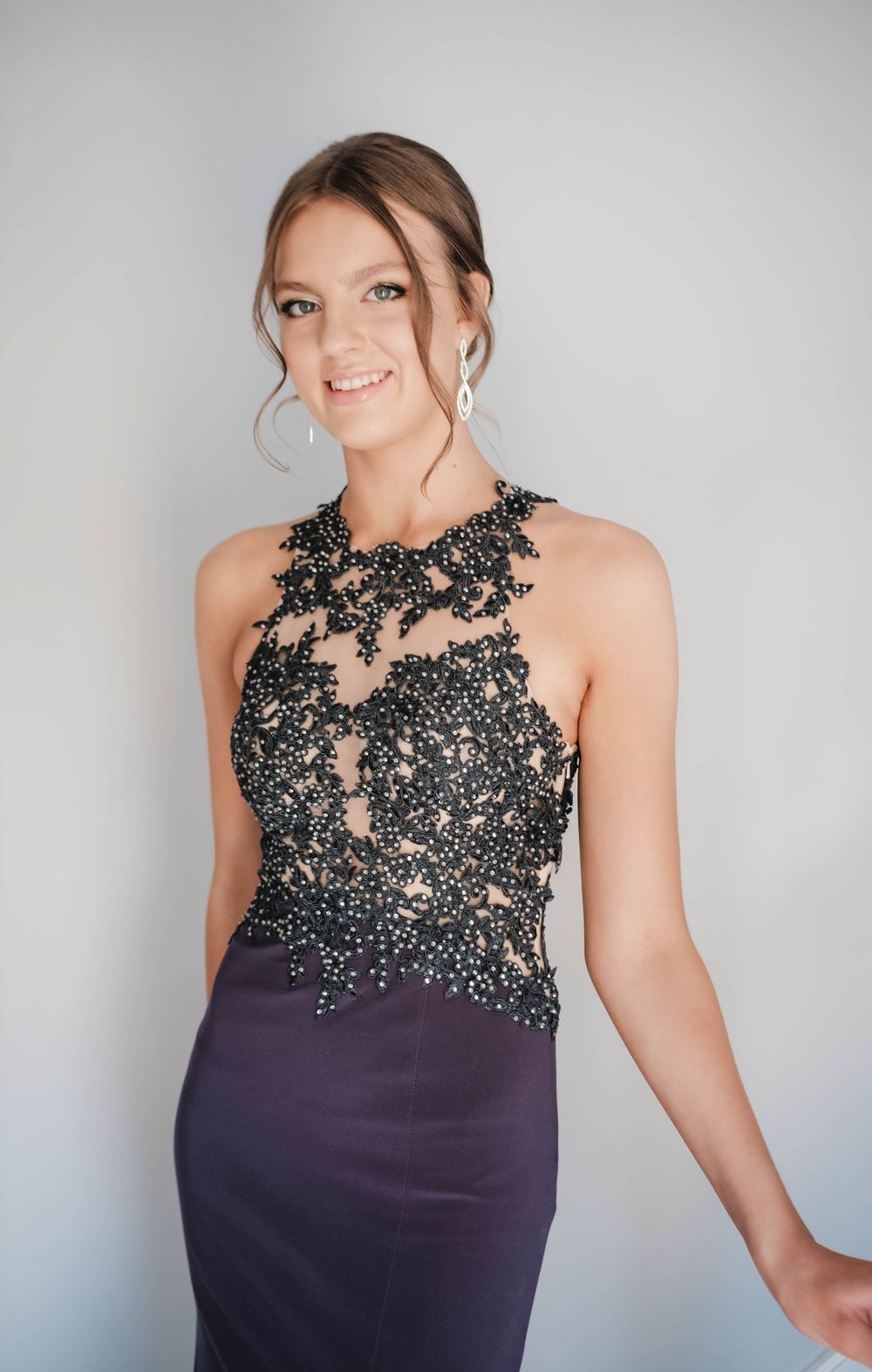 Portrait showcasing an elegant navy evening gown with intricate beaded lace detail.