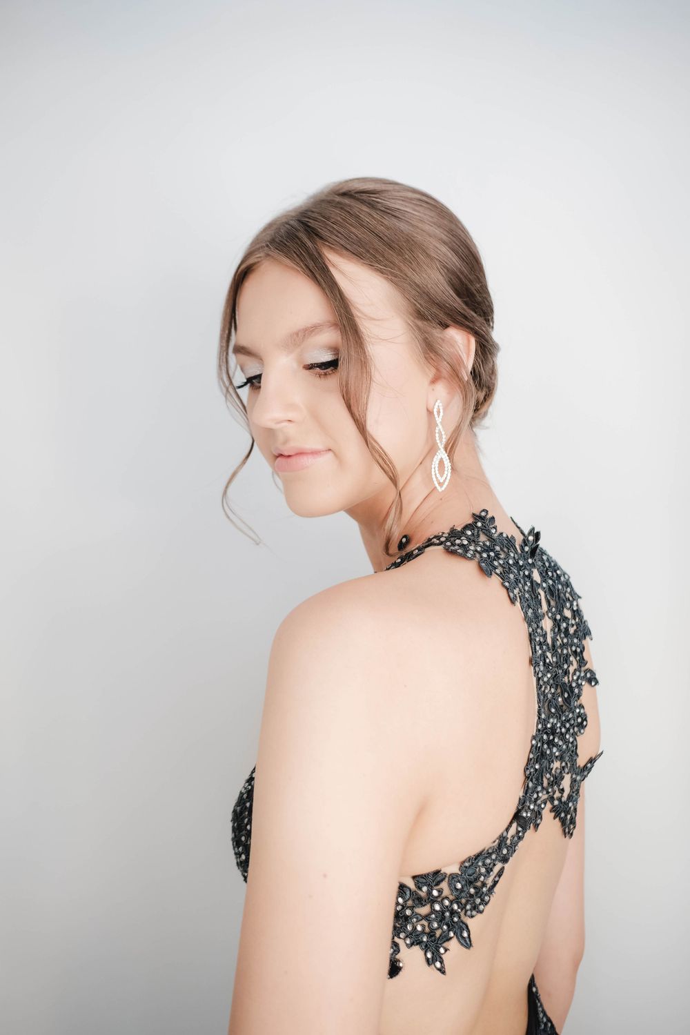 Elegant profile portrait highlighting dangling earrings and intricate lace neckline details.