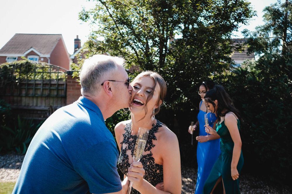 Candid outdoor moment between people at a formal event in a backyard setting.