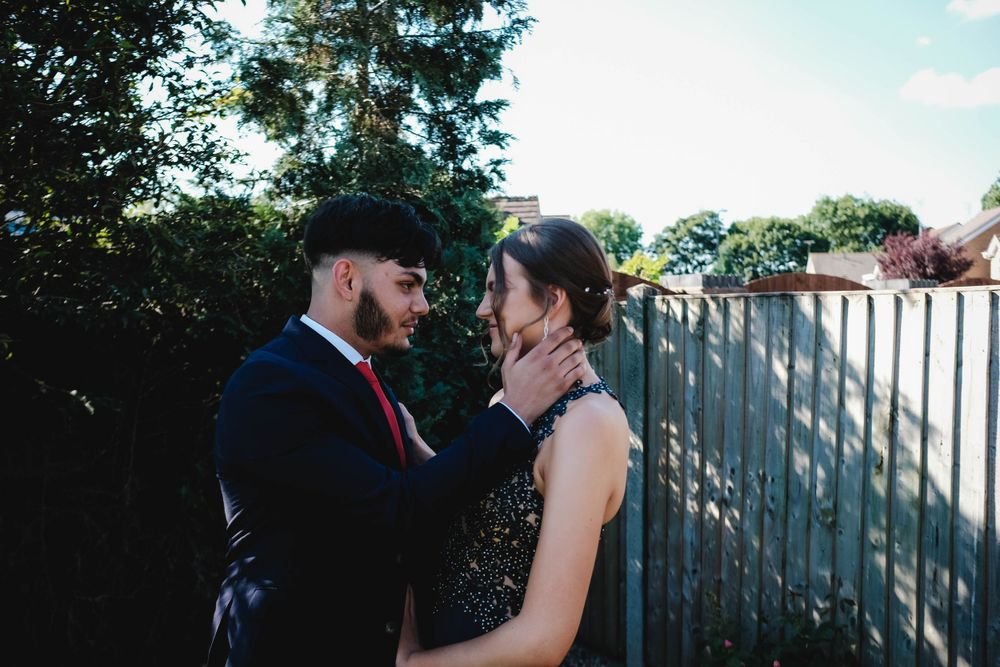 A romantic outdoor portrait of a couple sharing an intimate moment in formal attire.