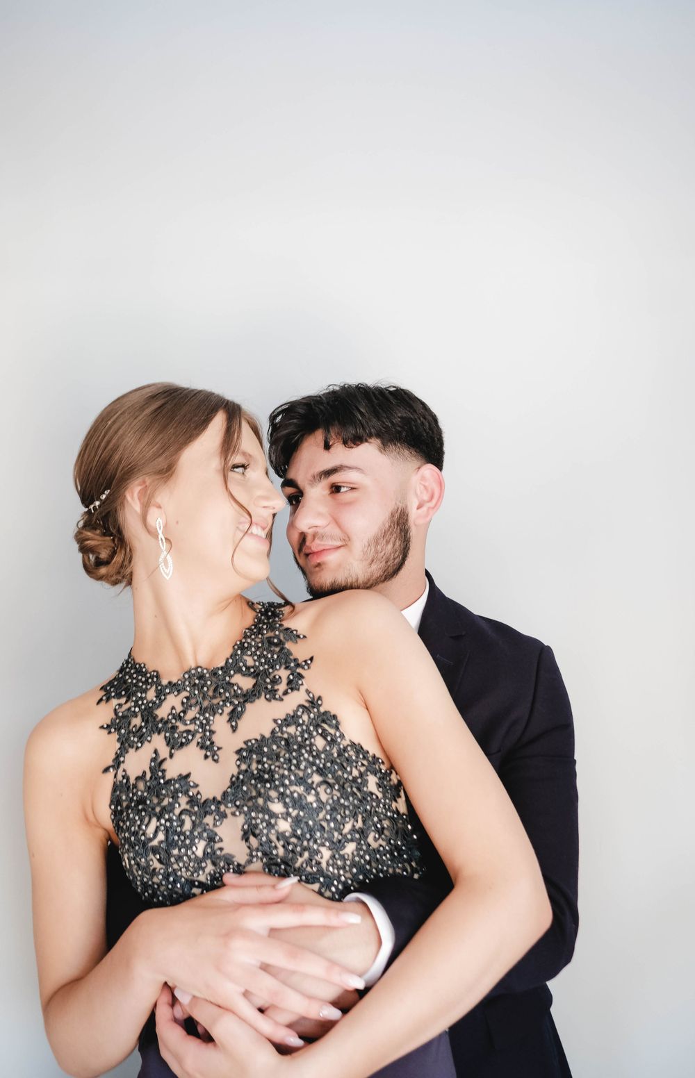 Intimate formal portrait of a couple in black attire against a white background.