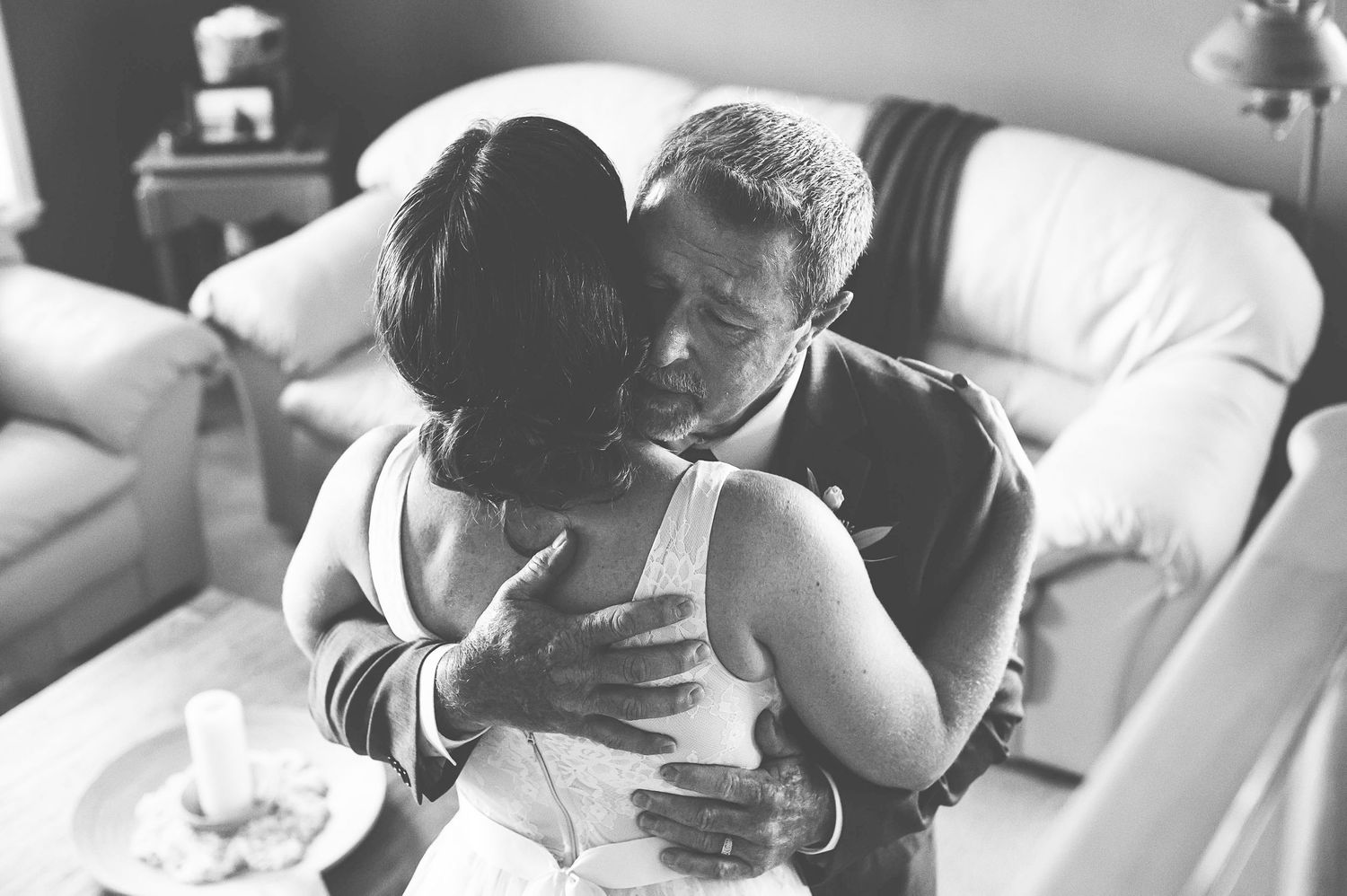 Black and white intimate photograph of a couple embracing on a couch.