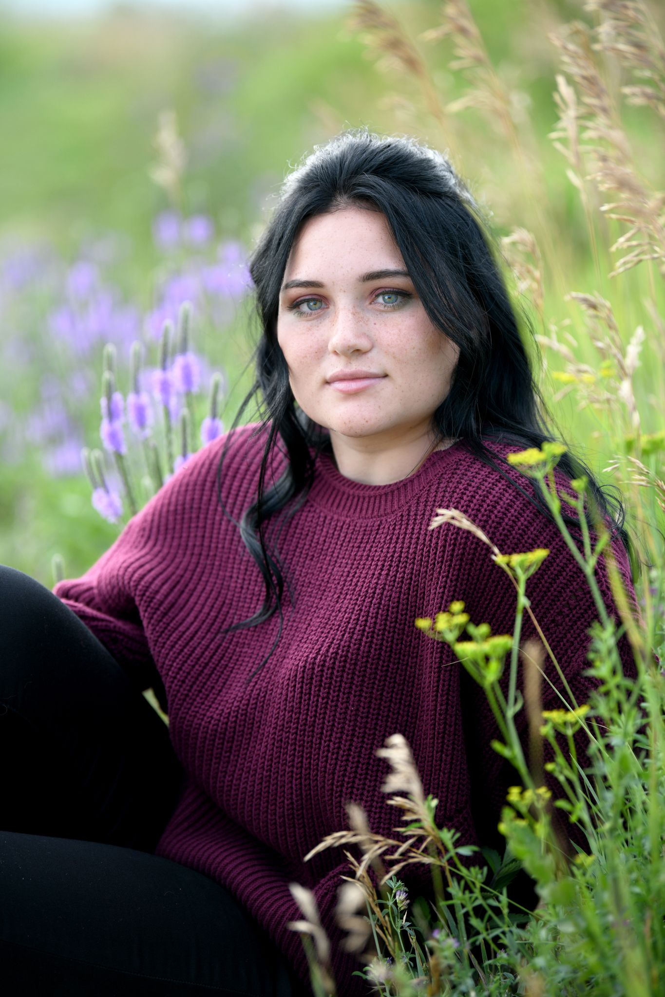 Portrait in a field of purple wildflowers with soft natural lighting and bokeh effect.