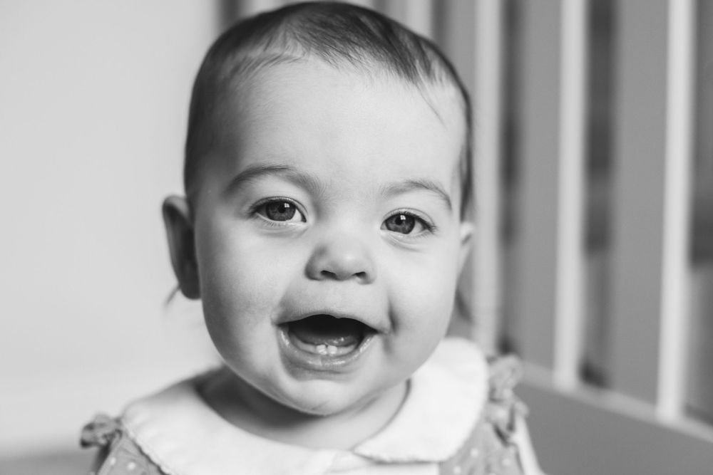 Close-up portrait of a smiling baby with bright eyes in black and white.