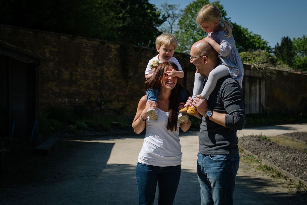 Family enjoying a sunny outdoor moment together near stone walls.