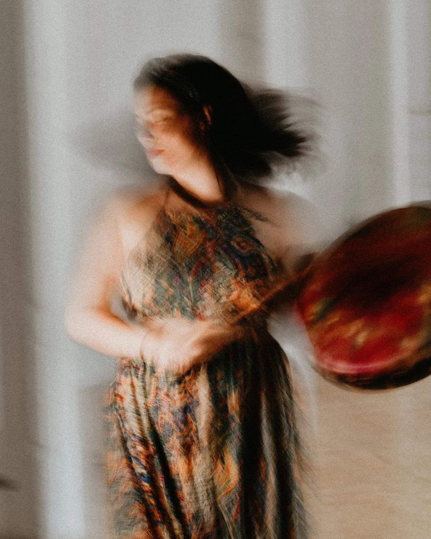 Artistic motion blur portrait of person in floral dress with flowing hair.
