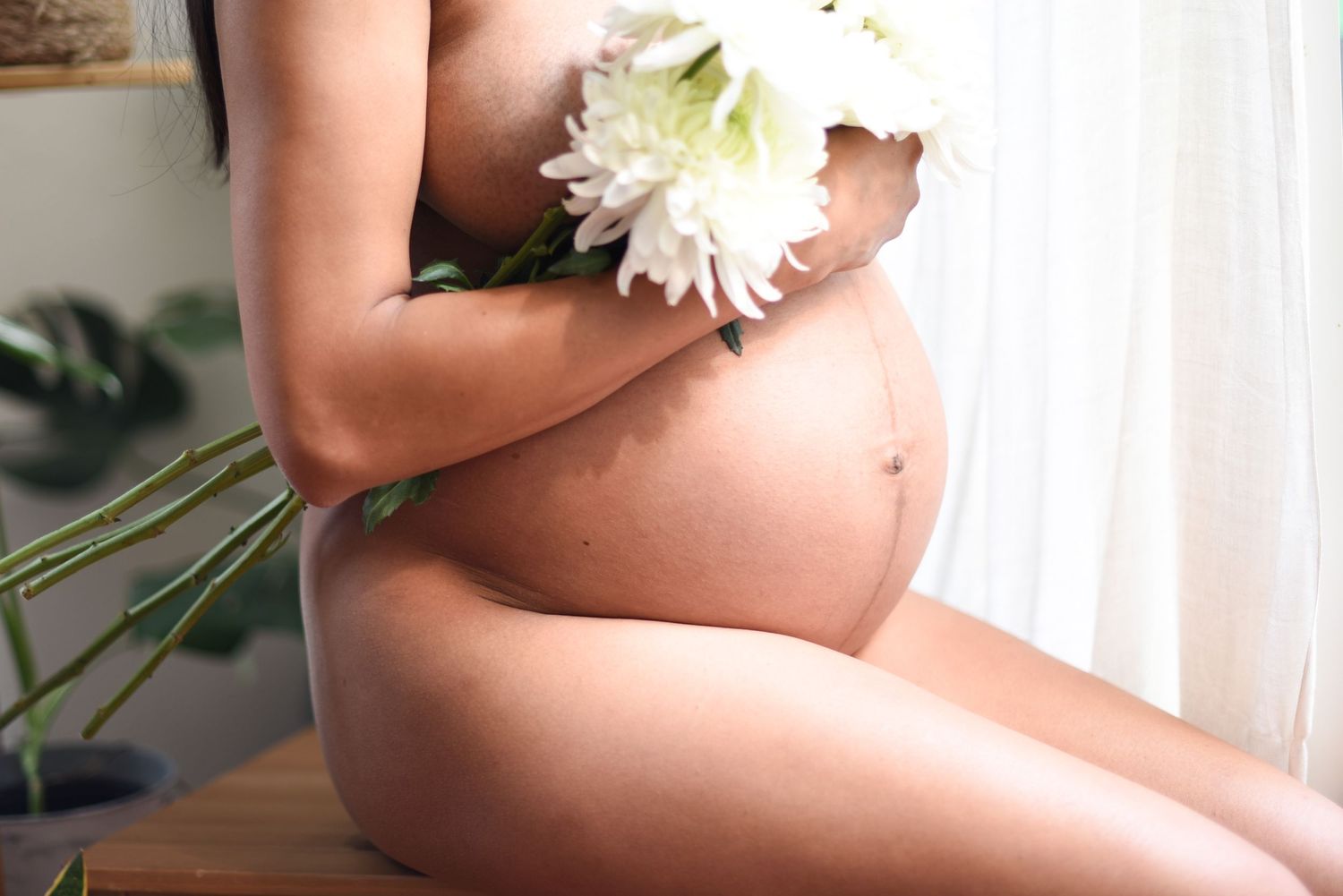 Intimate maternity portrait with white flowers and soft natural lighting.