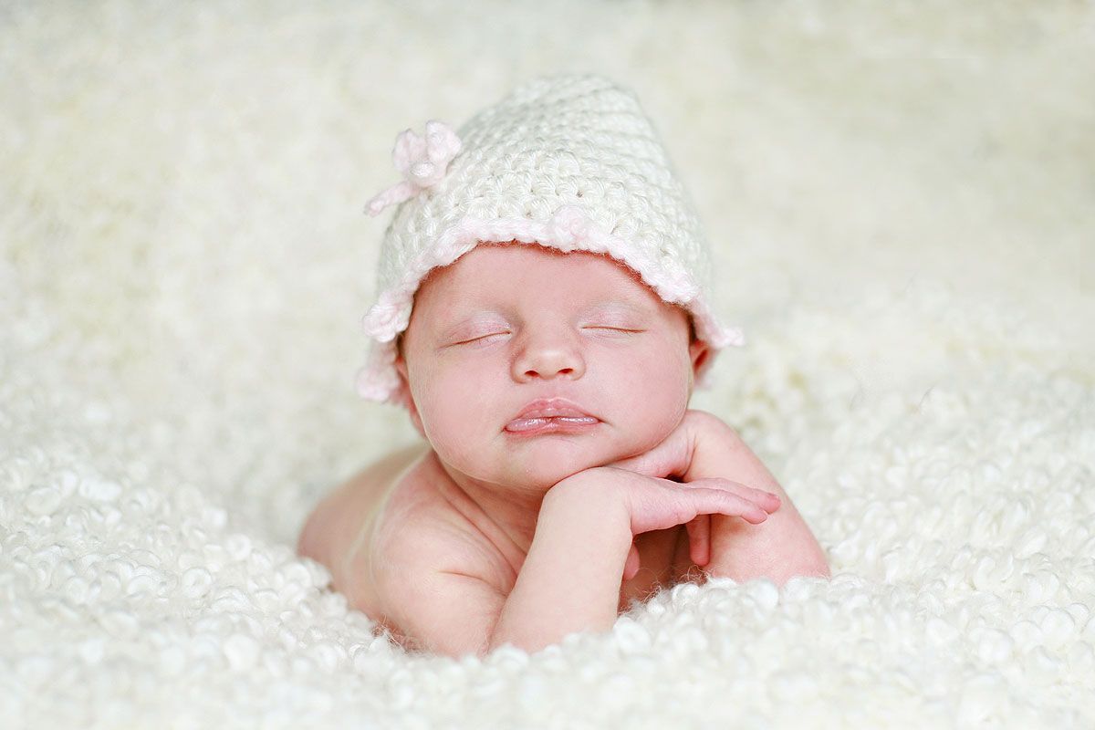 Photograph of Newborn Baby with hat posting on all white backdrop - Photos by Victoria Leigh Photography
