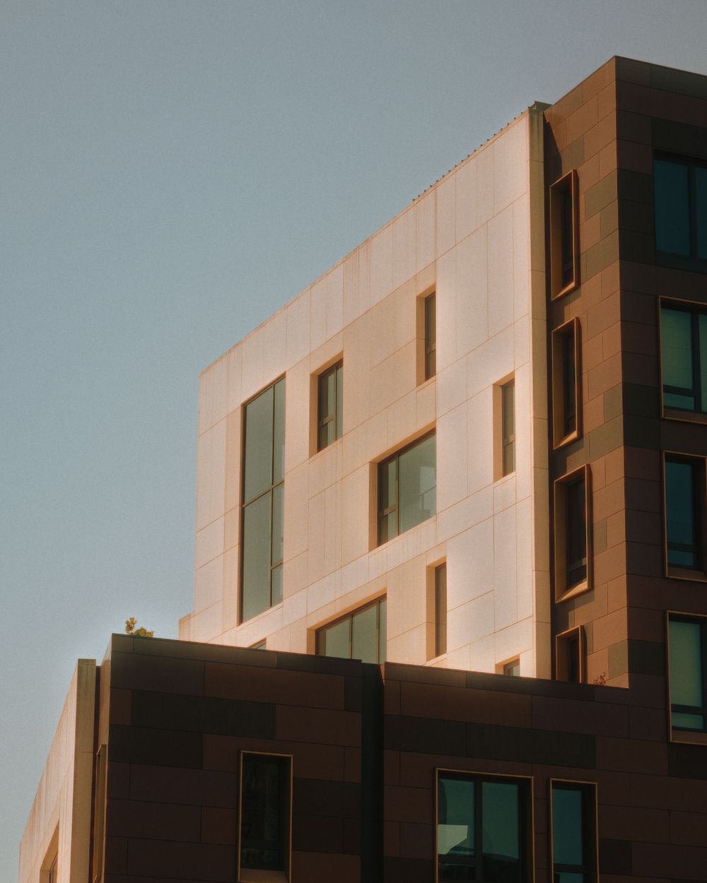 Modern architectural detail of a beige and brown building facade with geometric windows.