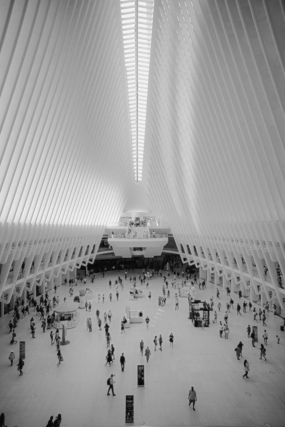 Black and white architectural photo of World Trade Center Oculus with people walking below.