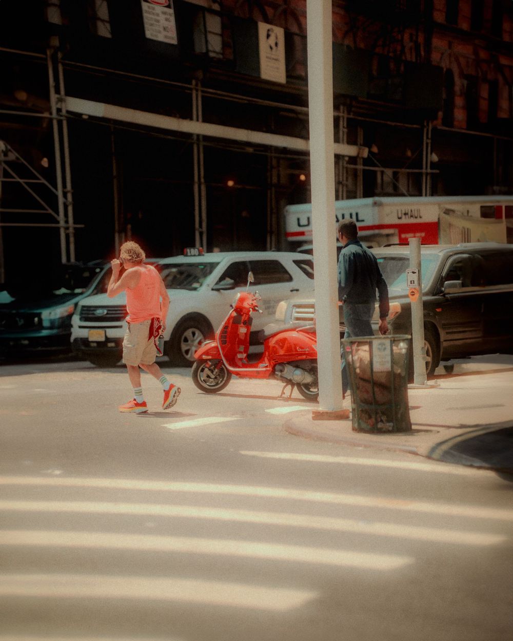 Street scene with parked cars and a red scooter in warm vintage tones.