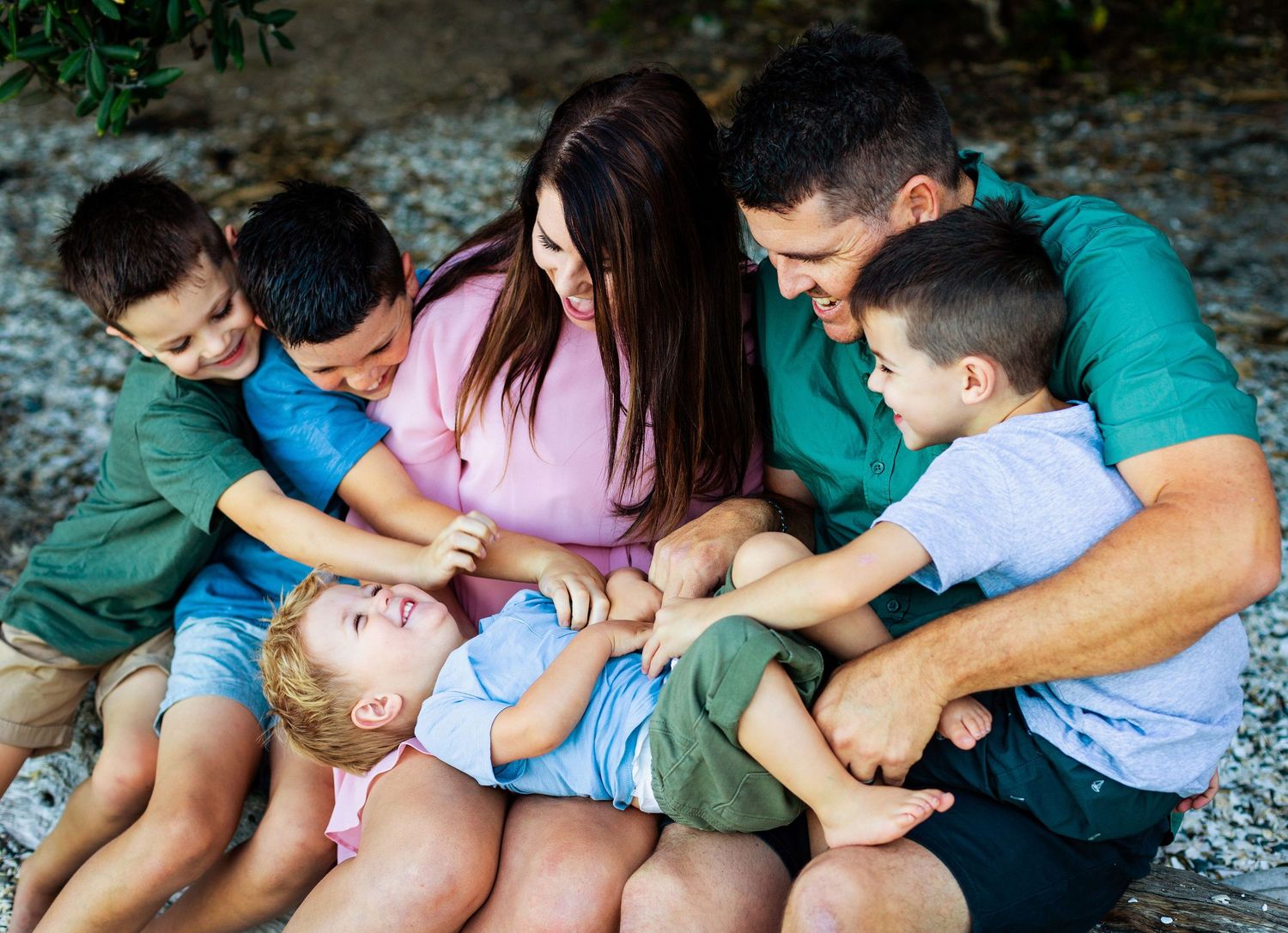 Family sharing a playful moment together while sitting on the ground outdoors.
