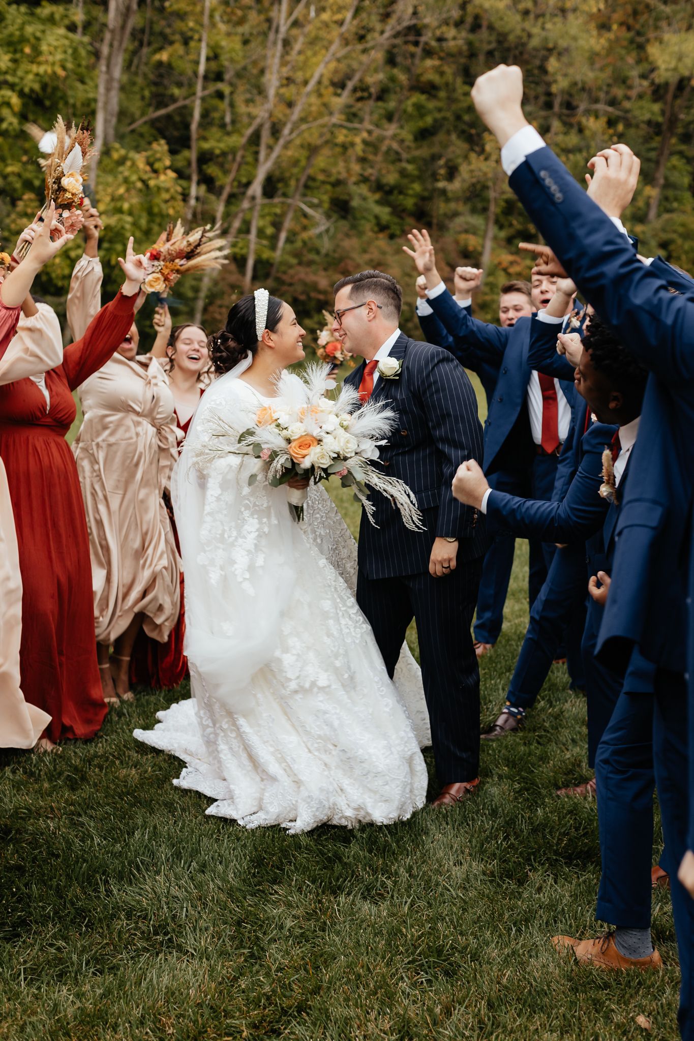 Wedding party celebrates with joyful jumping poses outdoors in formal attire.