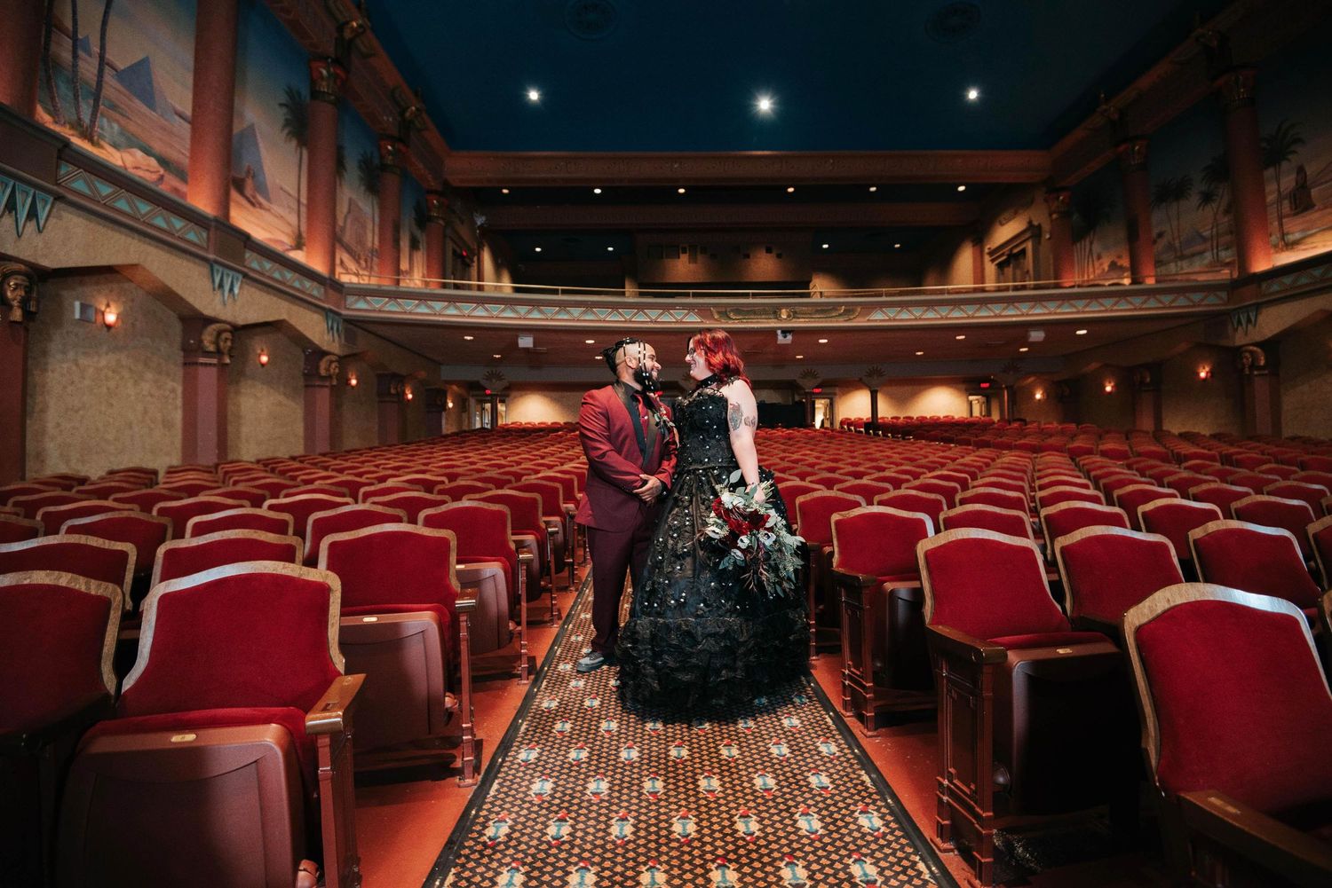 Historic theater interior with red velvet seats and ornate architectural details.