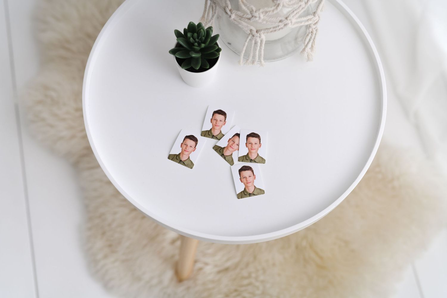 White ceramic plate with small photo cutouts and succulent plant on furry surface.