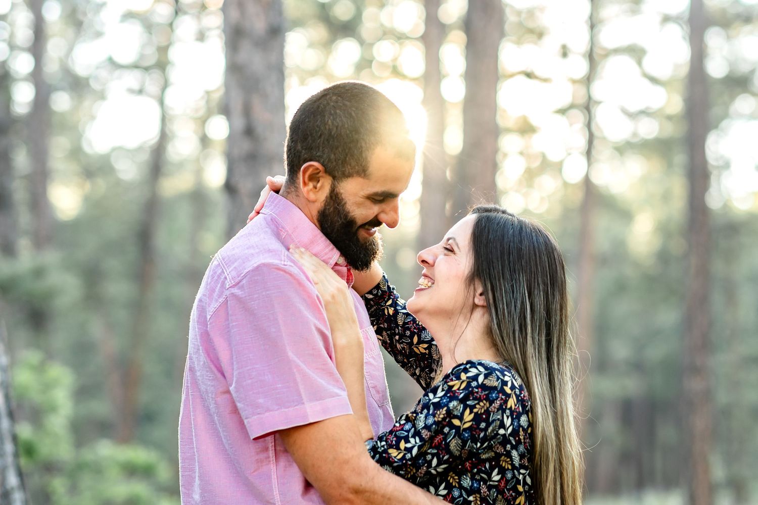 Husband and wife smile and laugh together at sunset during their family session in Colorado Springs.