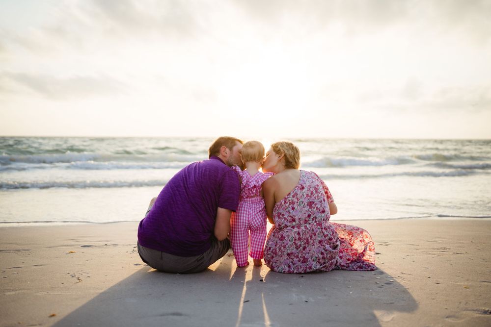 An intimate family moment shared while sitting on the beach at sunset.