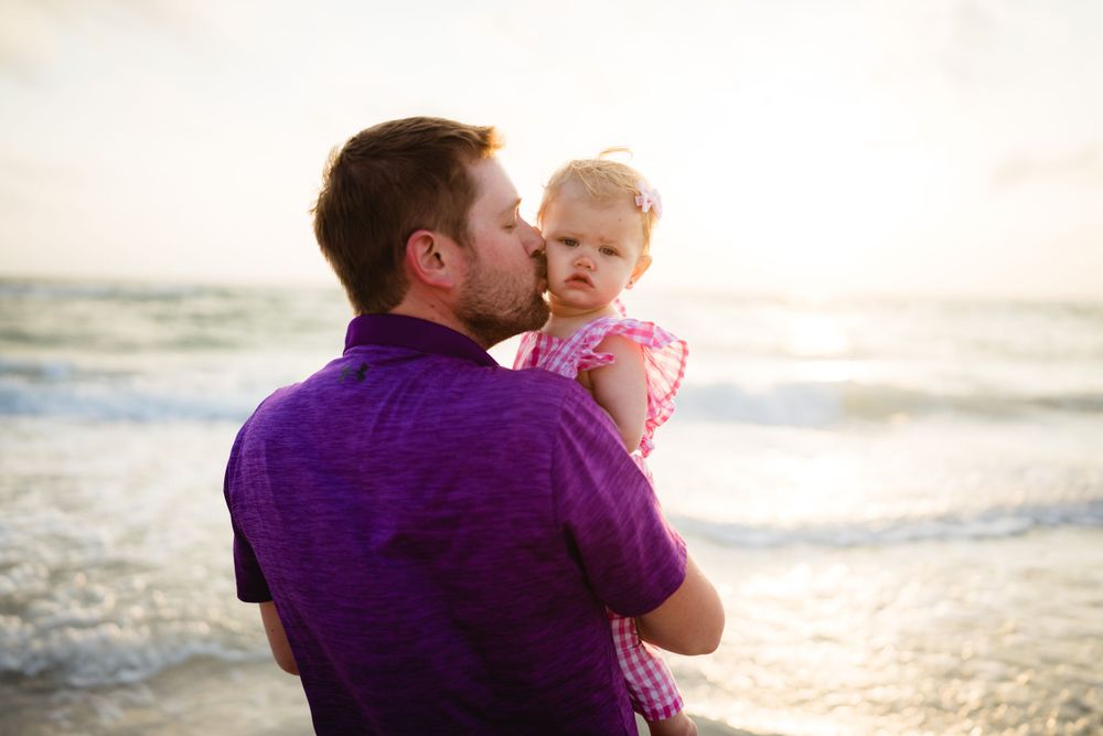 A tender moment shared between parent and child at sunset by the ocean.