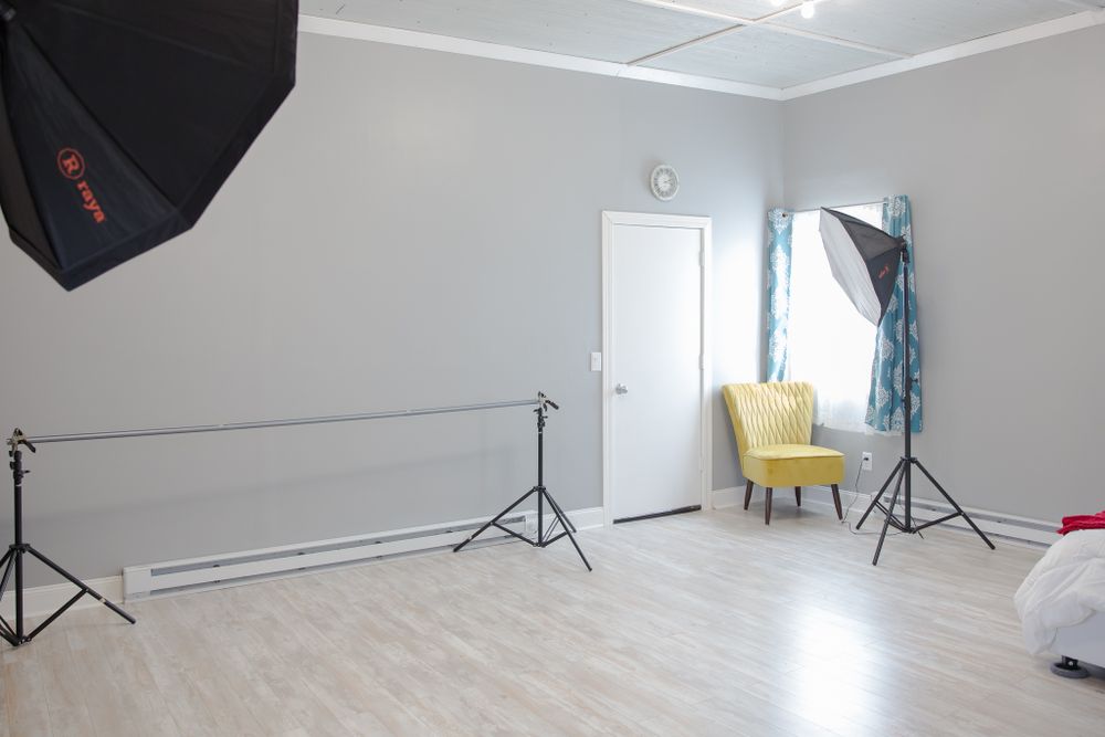 Clean photography studio space with lighting equipment, yellow accent chair, and white walls.