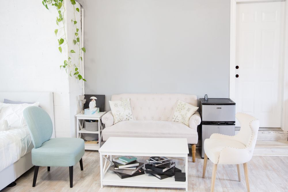 Modern photography studio lounge area with mint chair, white couch, and hanging plants.