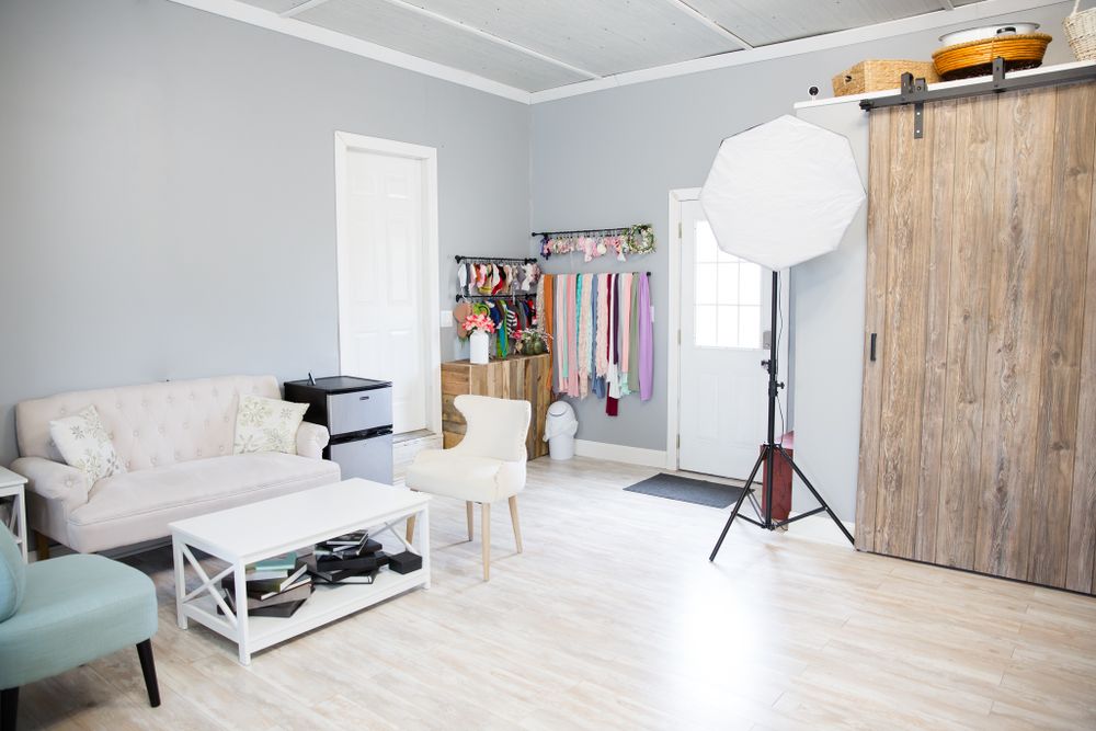 Photography studio interior with rustic barn door, seating area, and professional lighting equipment.