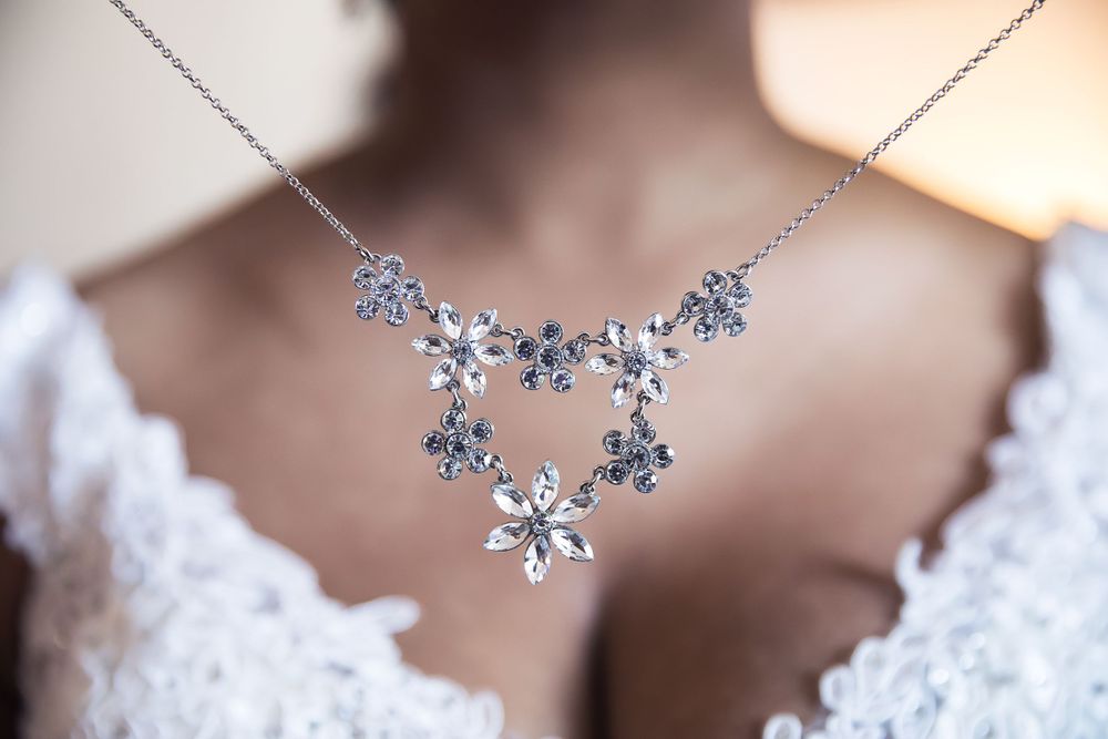Delicate silver snowflake necklace with crystal details worn against white lace fabric.