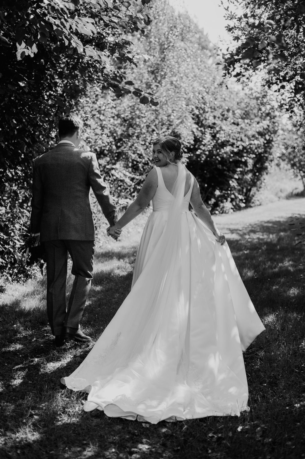 Bride looking back as they walk away from the camera in black and white at Hareston Manor