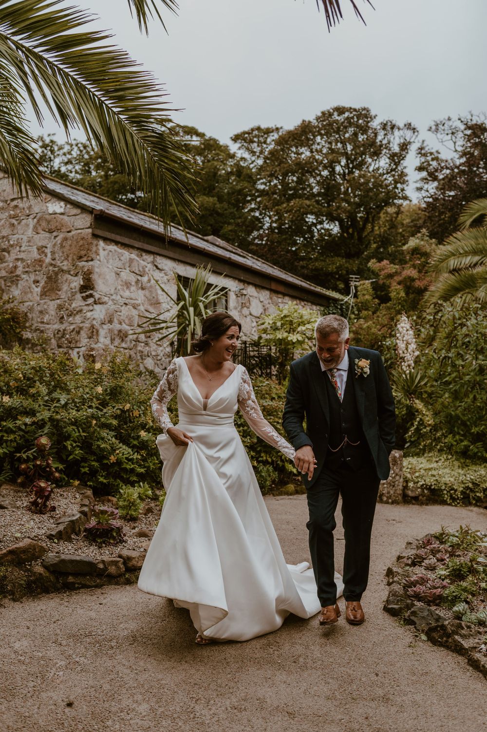 Wedding couple laughing as they walk through the grounds at Tregenna Castle