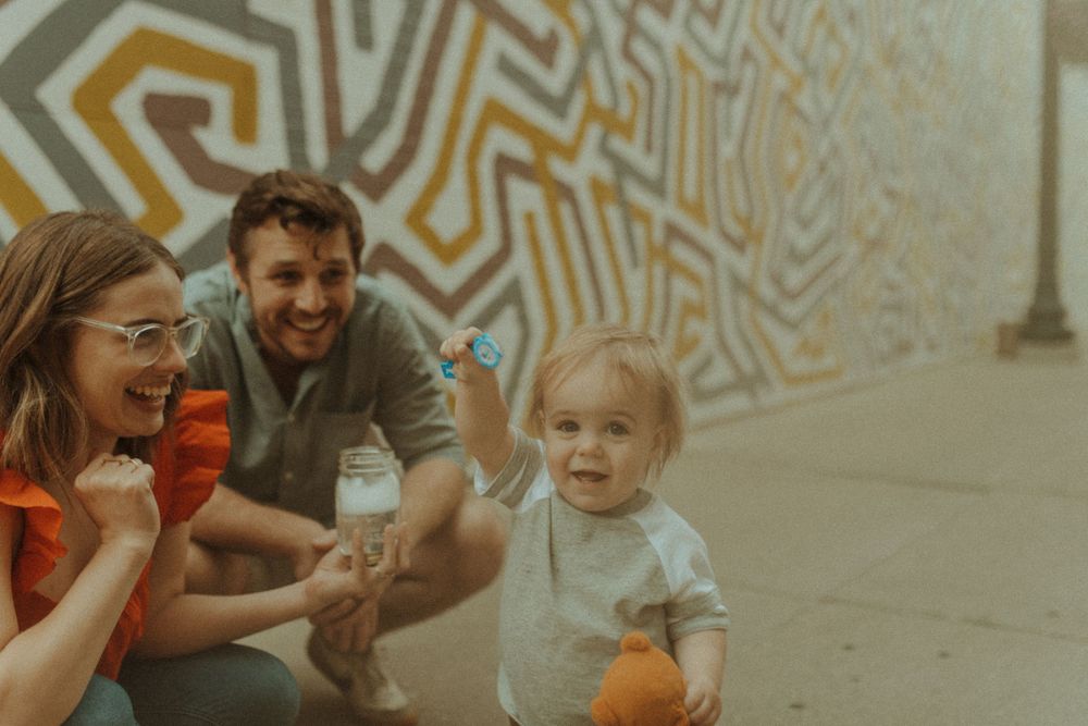 A joyful moment shared by a family sitting near a patterned wall mural.