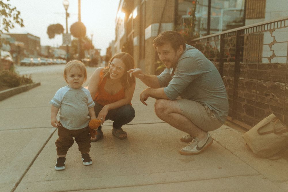 Family sharing a fun outdoor moment at sunset on city sidewalk.